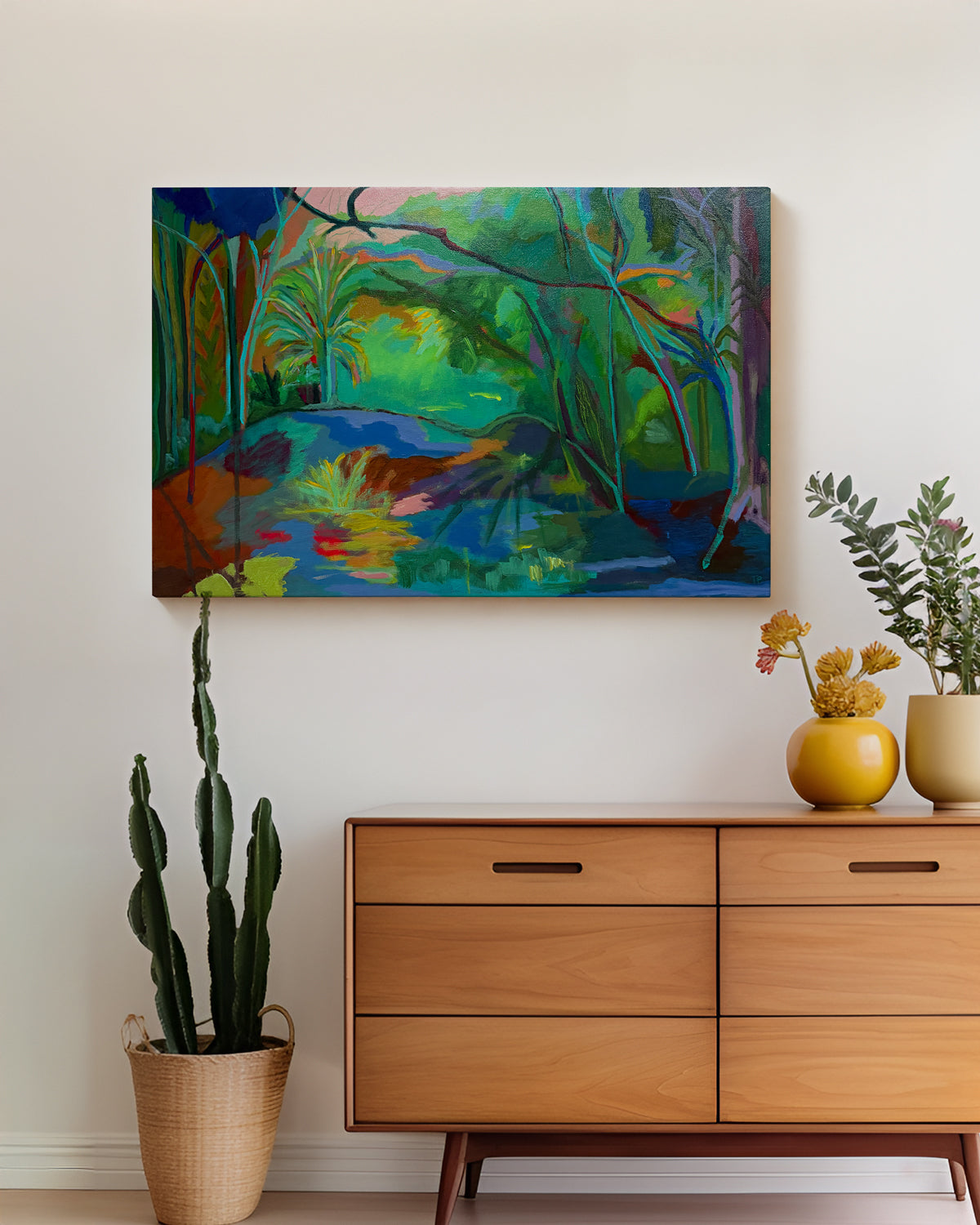Colorful abstract painting on a wall above a wooden dresser with plants. Lifestyle mockup shot. "Grassy Waters" is an original acrylic landscape painting by Terry Pesso, inspired by the lush color and reflective calm of Florida wetlands. Layered greens, blues, and subtle bursts of light create a sense of movement and depth, blending abstraction with a strong sense of place. This one-of-a-kind artwork is painted on a cradled wood panel and works beautifully as wall art decor. 