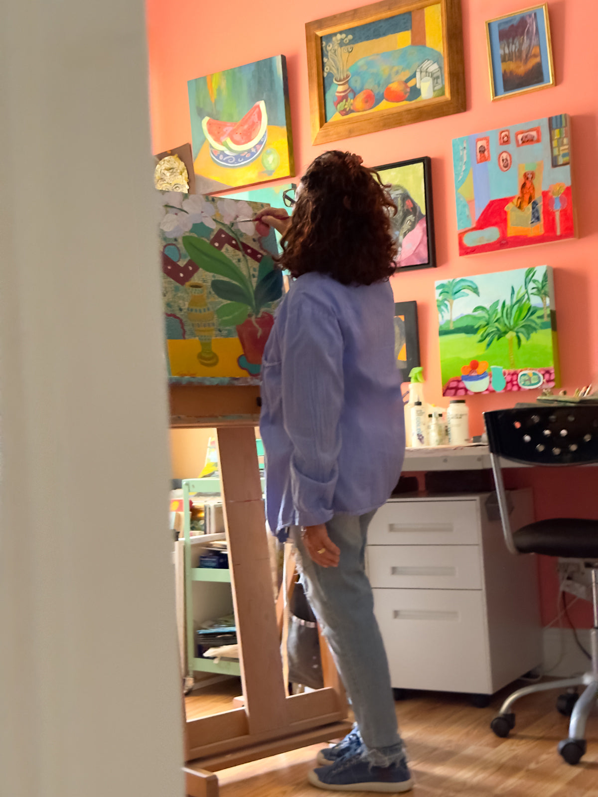 Person standing in a room with colorful paintings on the wall. Original painting by Terry Pesso created as collectible artwork for wall art decor. This contemporary mixed media piece is suitable for framed art and framed wall art in modern homes.