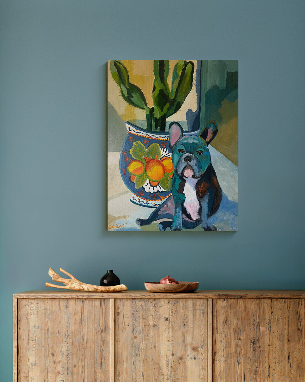Painting of a dog by a vase with fruit on a wall above a wooden cabinet. Lifestyle mockup. "Bear" is an original acrylic painting that captures the charm and character of a French Bulldog in bold, modern color. Deep teal, ochre, and coral tones bring the dog to life against a patterned ceramic pot and warm light. Each brushstroke adds energy and depth, blending realism with expressive style. This contemporary dog artwork makes a statement piece for any art lover or modern home.